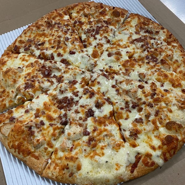 A Hindsight Pizza chicken bacon ranch pizza, cut into slices, in a cardboard box.